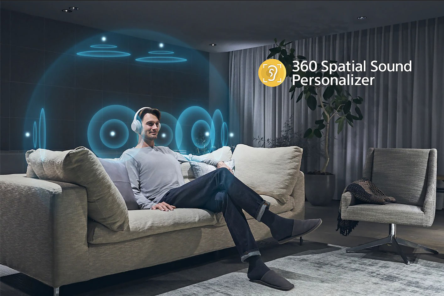 Una persona sentada en un sofá con los audífonos ULT WEAR y una pantalla con comentarios del Sony | 360 Spatial Sound Personalizer.