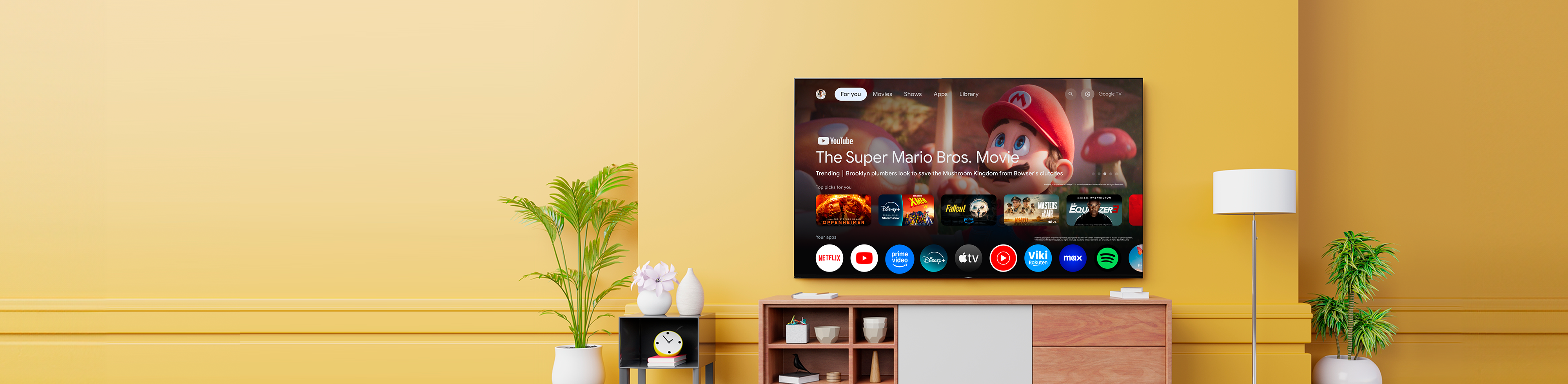 Televisor grande instalado en la pared que muestra la interfaz de Google TV con Super Mario Bros.: la película. Las aplicaciones de streaming se presentan a continuación.